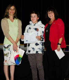 NGPS Trustee Anita Portsmouth (left) and NGPS Assistant Superintendent Leslee Jodry (right) present Fox Creek junior high school student, Jacob Scobey with the NGPS Award Junior High School!